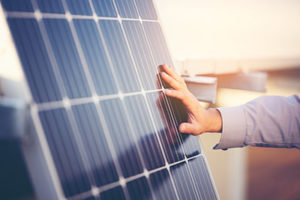 Close up of engineer hand is checking an operation of sun and cleanliness of photovoltaic solar panels on a sunset. Concept: renewable energy, technology,electricity,service, green,future